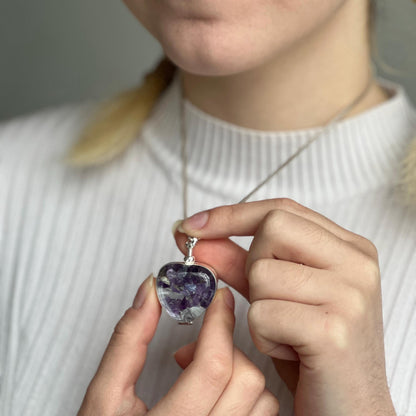 silver plated heart locket necklace with stones inside being worn by model with blonde hair