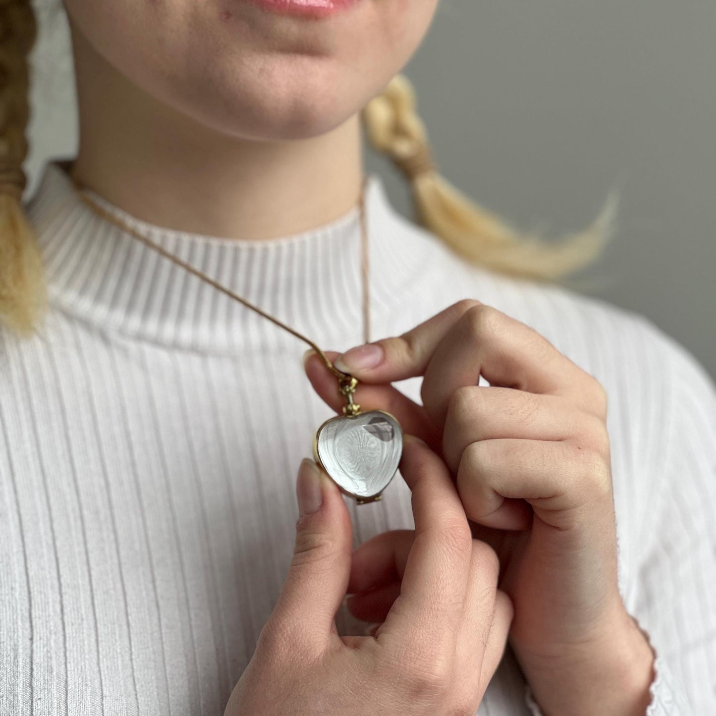 gold heart locket necklace being worn by model with blonde hair