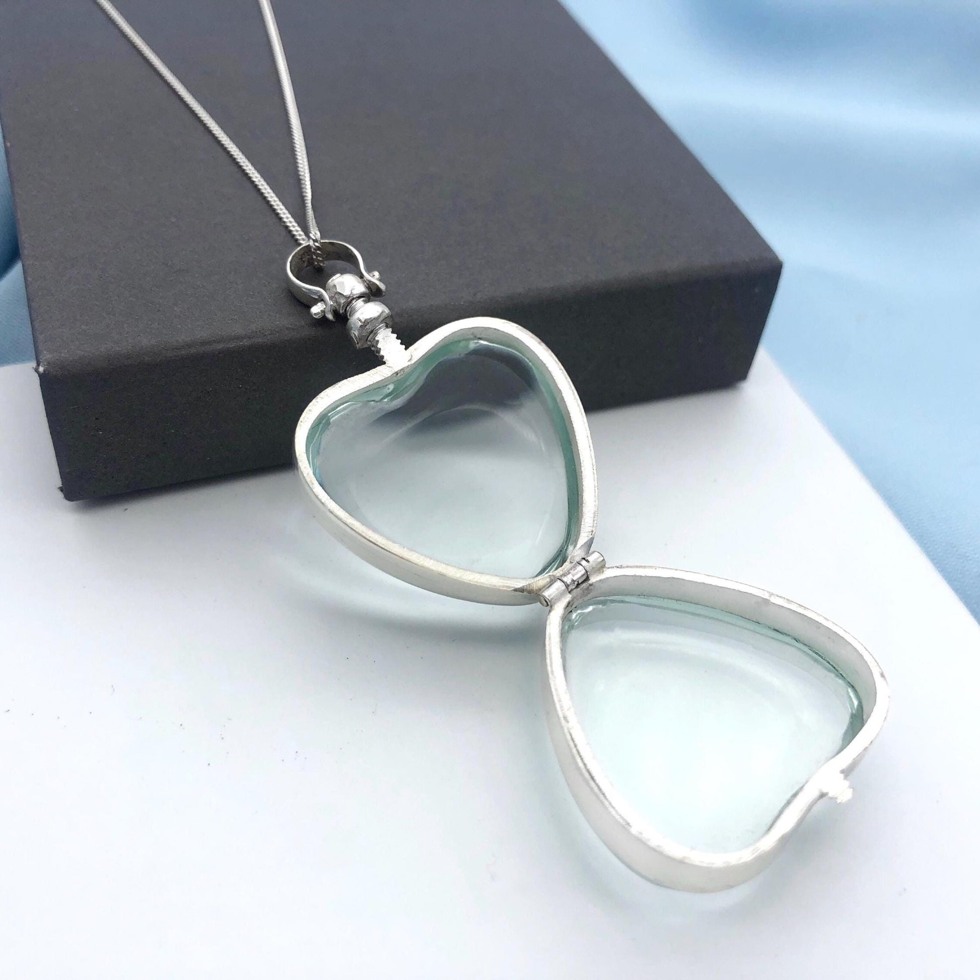large deep silver plated locket in open position on gift box
