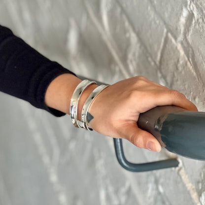 model wearing thick double stripe silver bangle while holding onto bannister